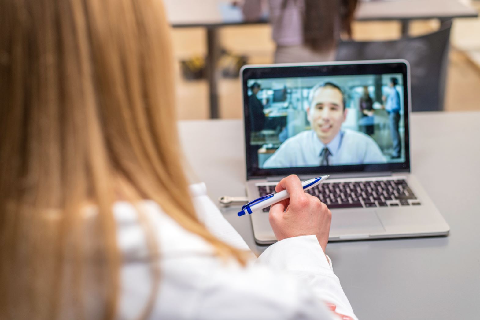 Frau hört sich ein Online-Webinar am Laptop an