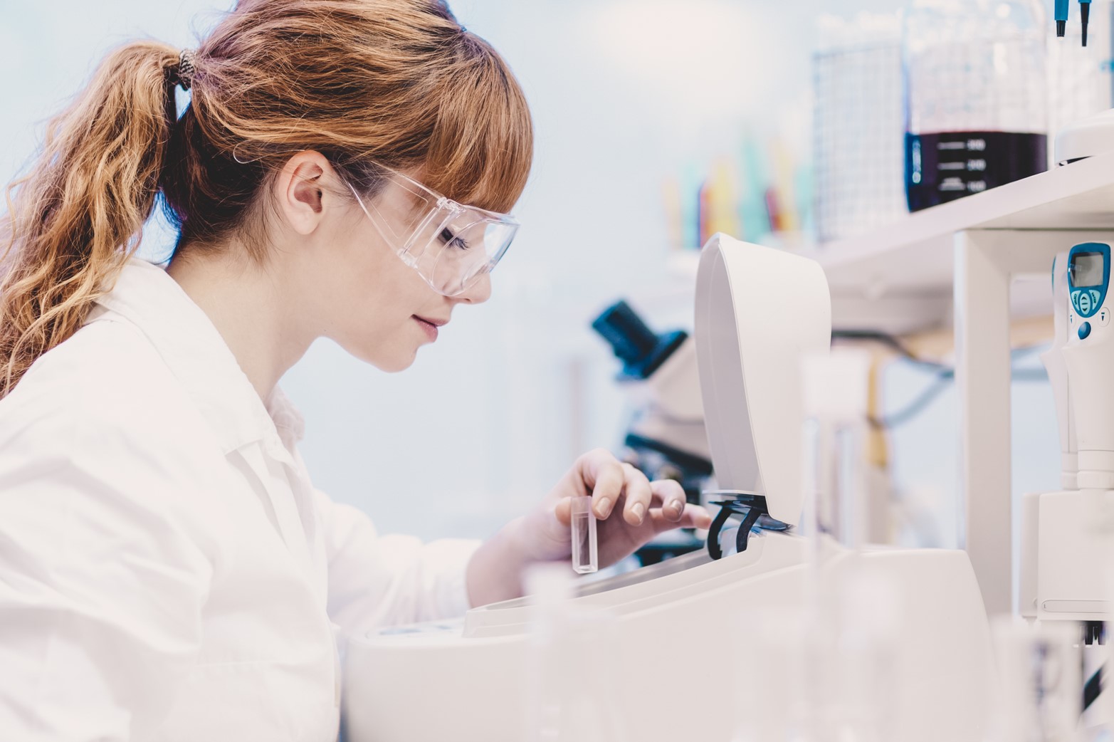 Woman in a laboratory placing a cuvette in a medical device
