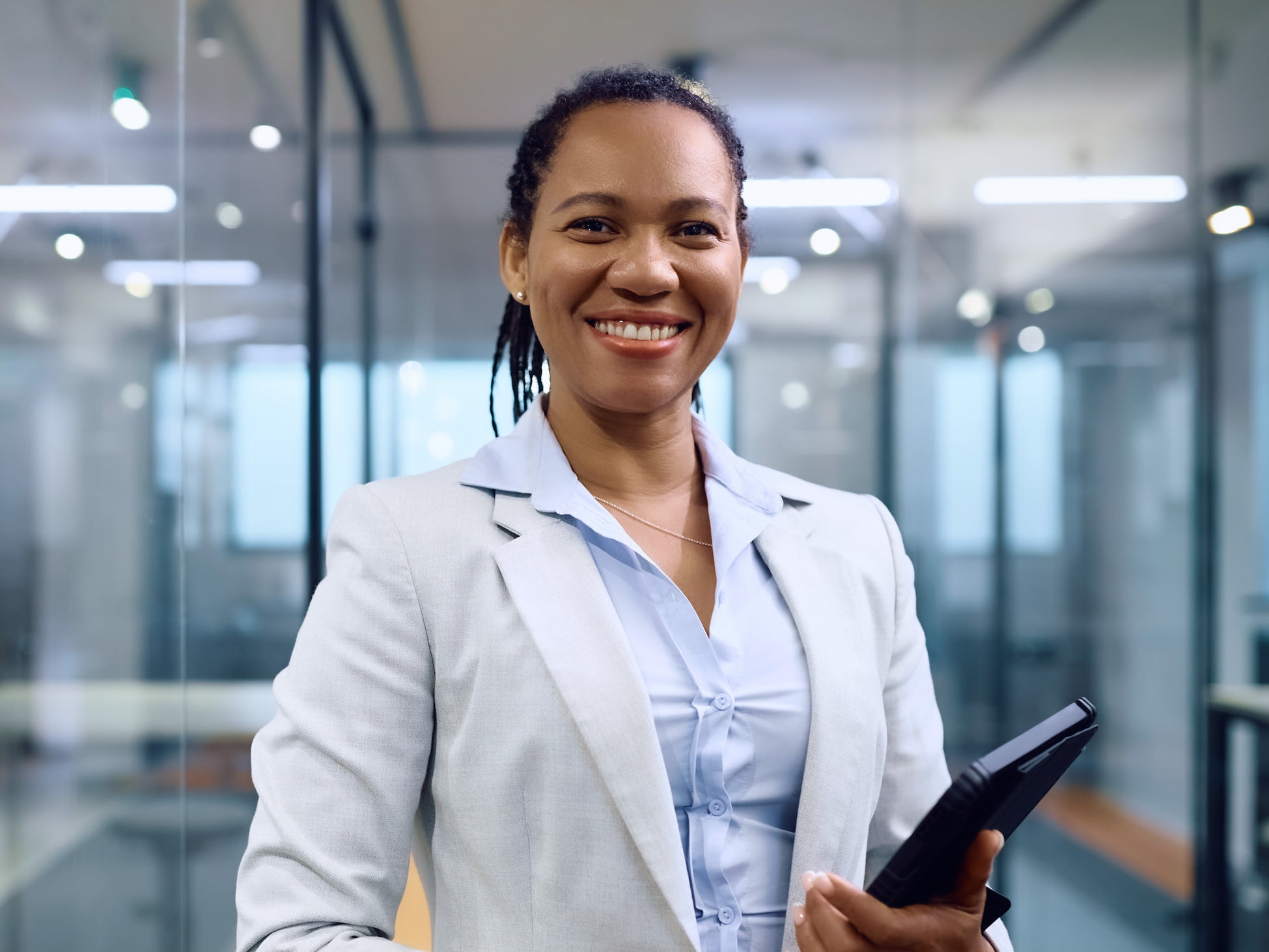 Businesswoman looking and smiling at the camera, holding a tablet.